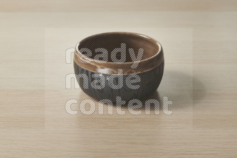 A multicolored pottery bowl on light wooden background