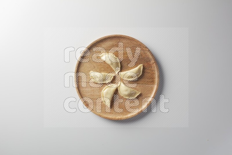Five Sambosas on a wooden round plate on a white background