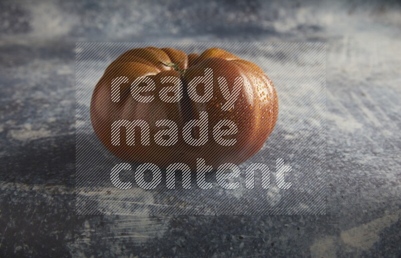 45 degree single heirloom tomato on a textured rustic blue background