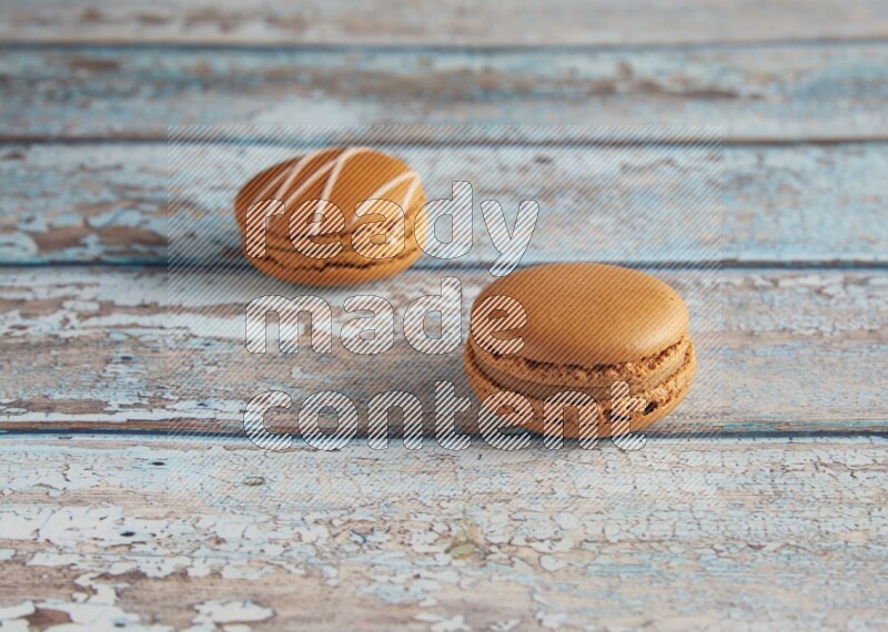 45º Shot of of two assorted Brown Irish Cream, and Brown Maple Taffy macarons  on light blue background