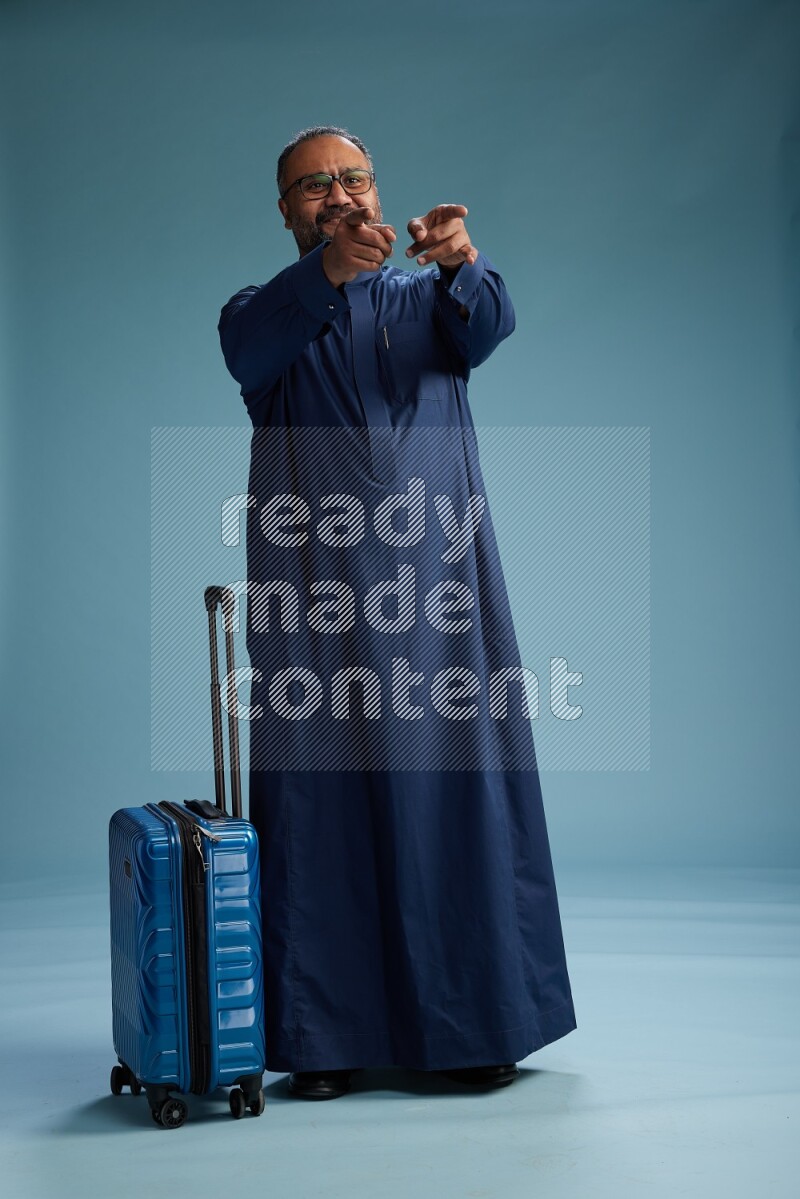 Saudi Man without shimag Standing pulling travel bag on blue background