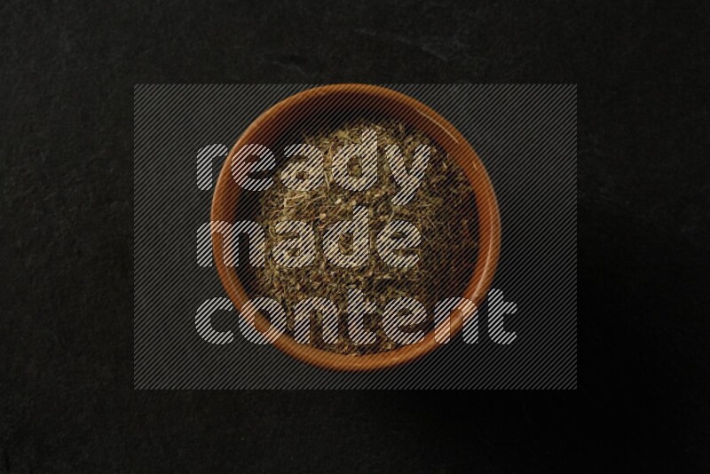 wooden round sauce bowl filled with herbs on grey textured countertop