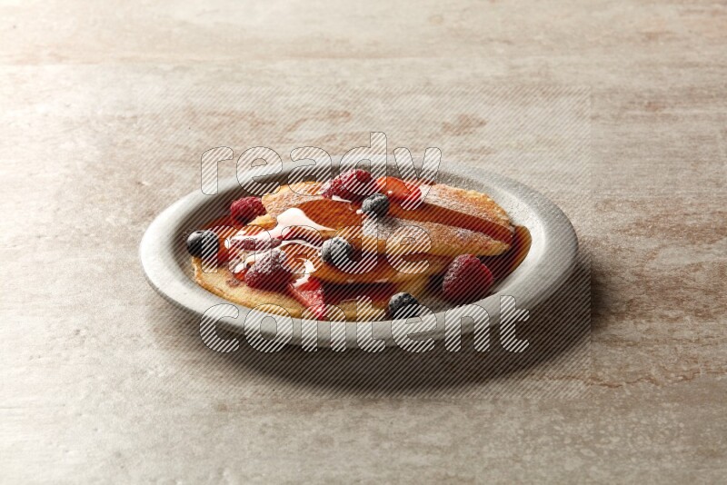 Three stacked mixed berries pancakes in a grey plate on beige background