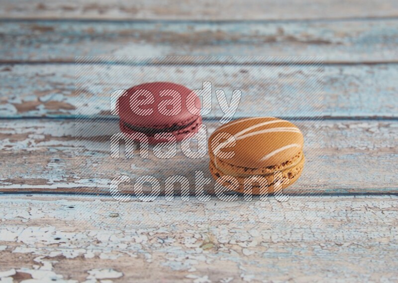 45º Shot of of two assorted Brown Irish Cream, and Red Cherry macarons  on light blue background