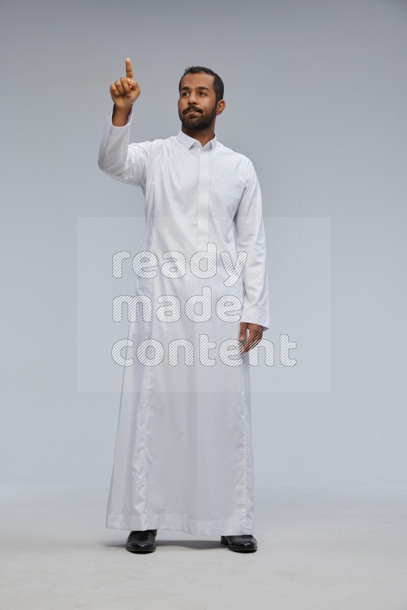 Saudi man Wearing Thob standing interacting with the camera on Gray background