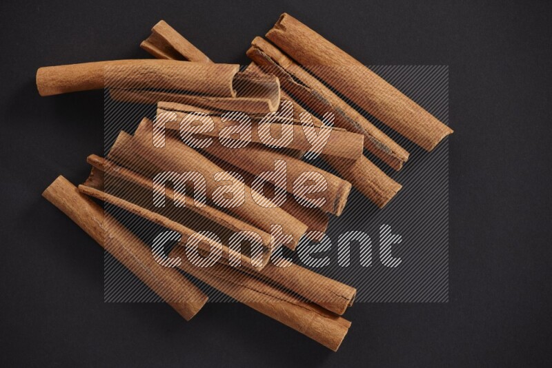 Cinnamon sticks stacked on black flooring