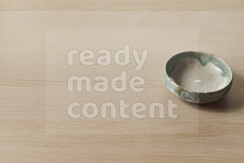 A multicolored pottery bowl on light wooden background