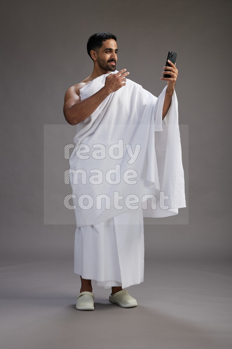 A man wearing Ehram Standing taking selfie on gray background