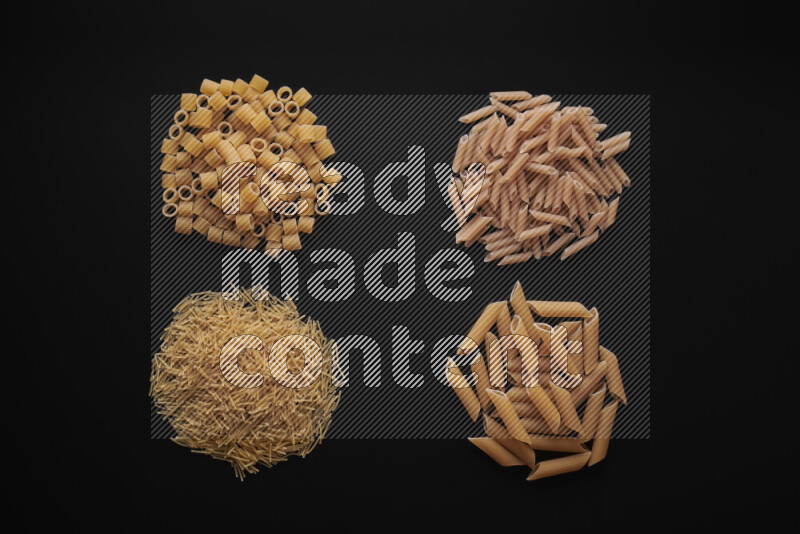 Different pasta types in bunches on black background