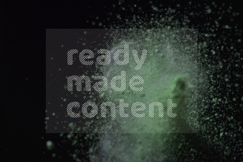 Green powder explosion on black background