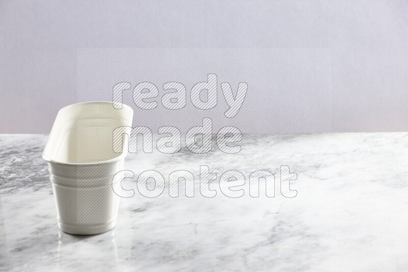 An empty white plant pot on grey marble background