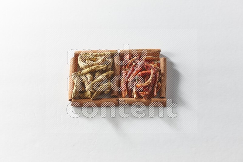 2 squares of cinnamon sticks full of dried red chilis and turmeric fingers on white flooring