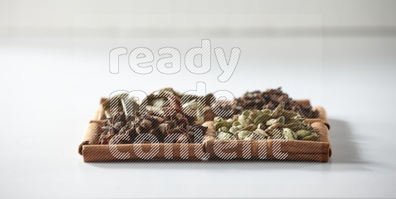 4 squares of cinnamon sticks full of cardamom, star anise, cloves and bay laurel leaves on white flooring