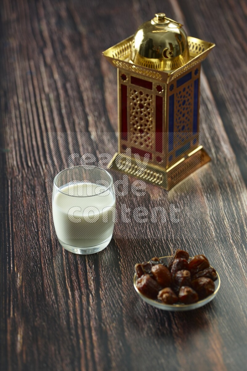 A golden lantern with different drinks, dates, nuts, prayer beads and quran on brown wooden background