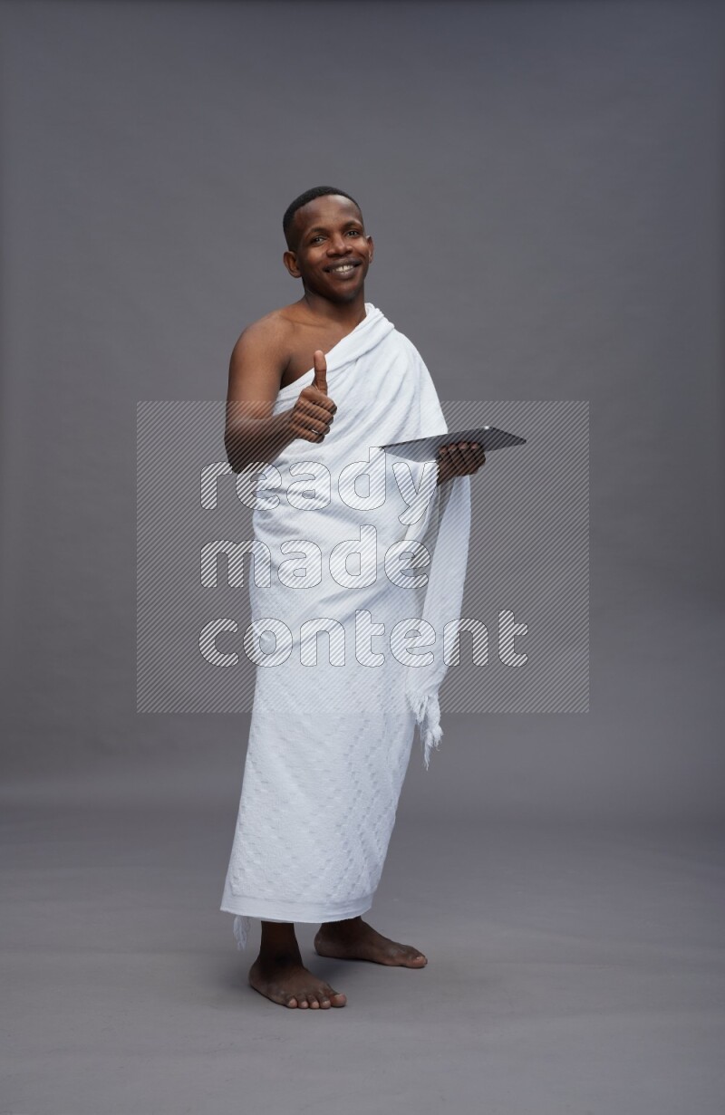 A man wearing Ehram Standing working on tablet on gray background