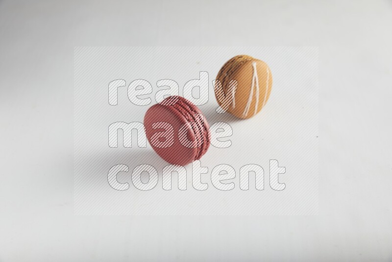 45º Shot of of two assorted Brown Irish Cream, and Red Velvet macarons on white background