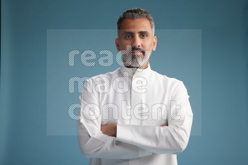 Saudi man waring thob posing to the camera on blue background