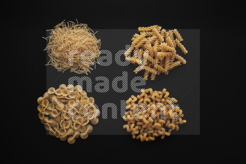 Different pasta types in bunches on black background