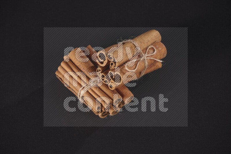 Two bounded stacks of cinnamon sticks on black background