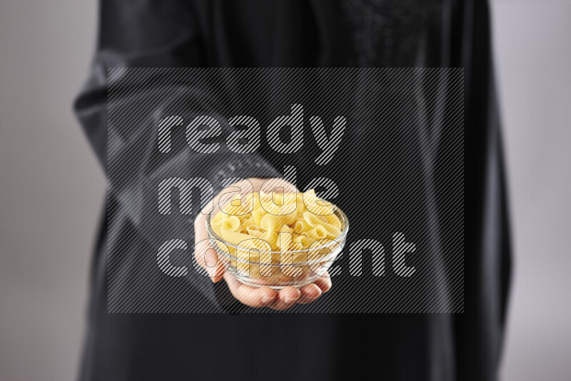 Woman in abaya holding different kinds of pasta in different positions