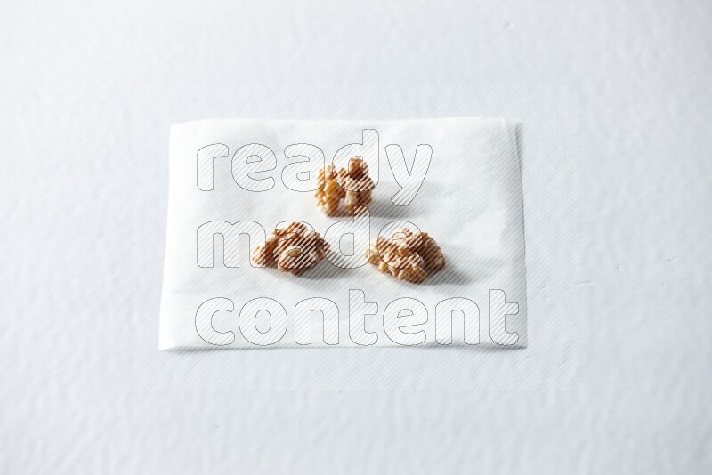 3 peeled walnuts on a piece of paper on a white background in different angles