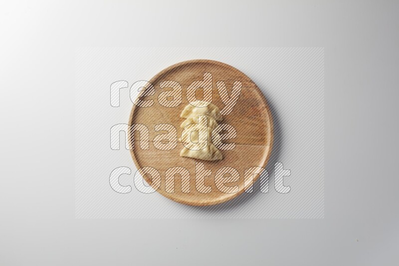 Four Sambosas on a wooden round plate on a white background