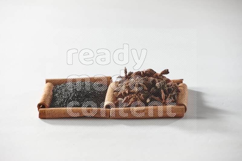 2 squares of cinnamon sticks full of black seeds and star anise on white flooring