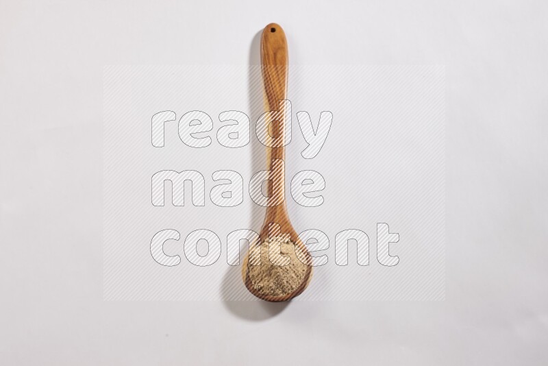 A wooden ladle full of garlic powder on a white flooring