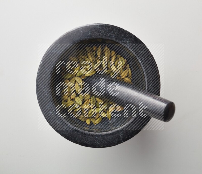 Top-view shot of Cardamon in herbs crusher on white background