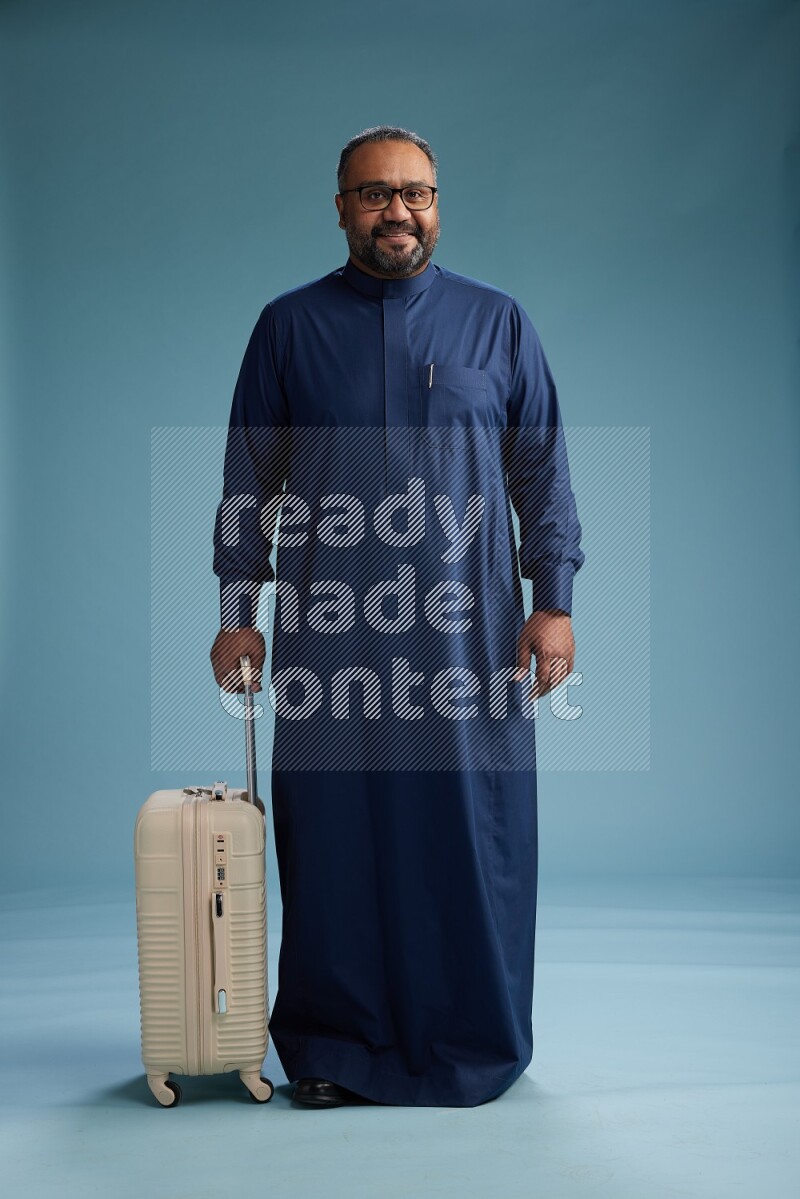 Saudi Man without shimag Standing pulling travel bag on blue background