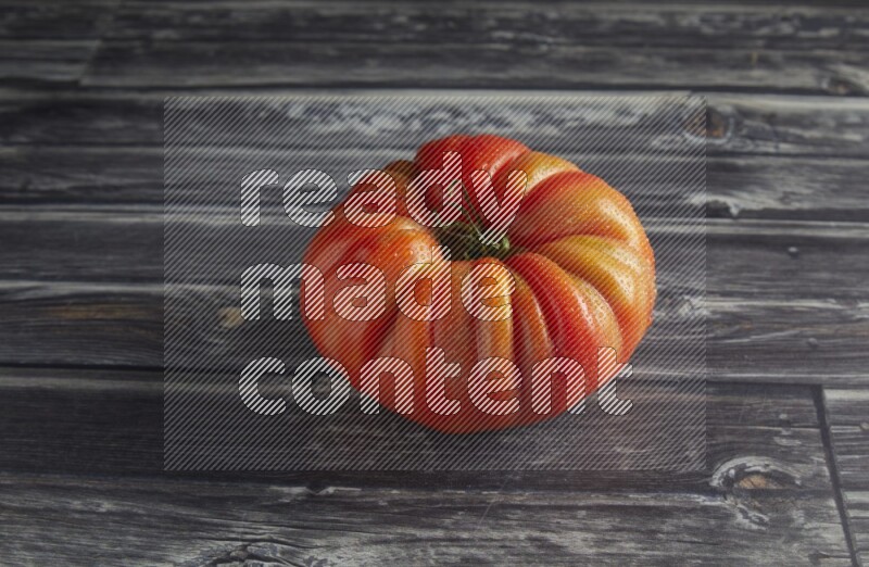45 degree single heirloom tomato on a textured grey wooden background