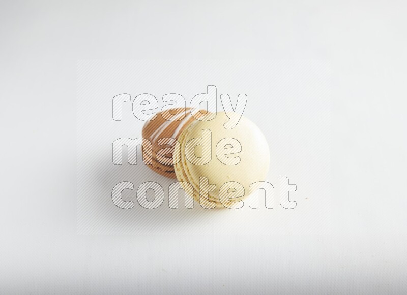 45º Shot of of two assorted Brown Irish Cream, and Yellow Vanilla macarons on white background