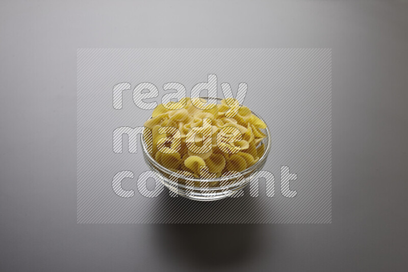 Fiocchi pasta in a glass bowl on grey background
