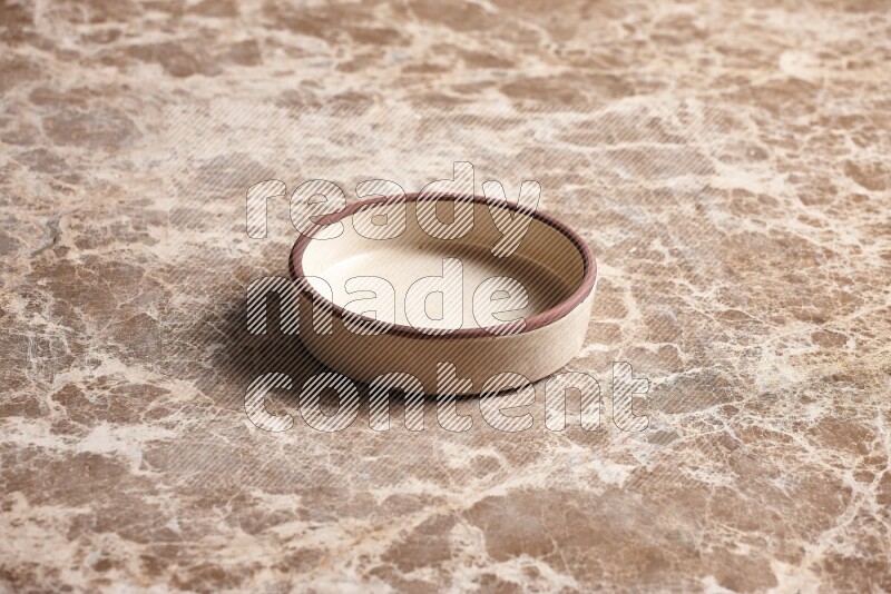 A beige pottery oven plate on beige marble background