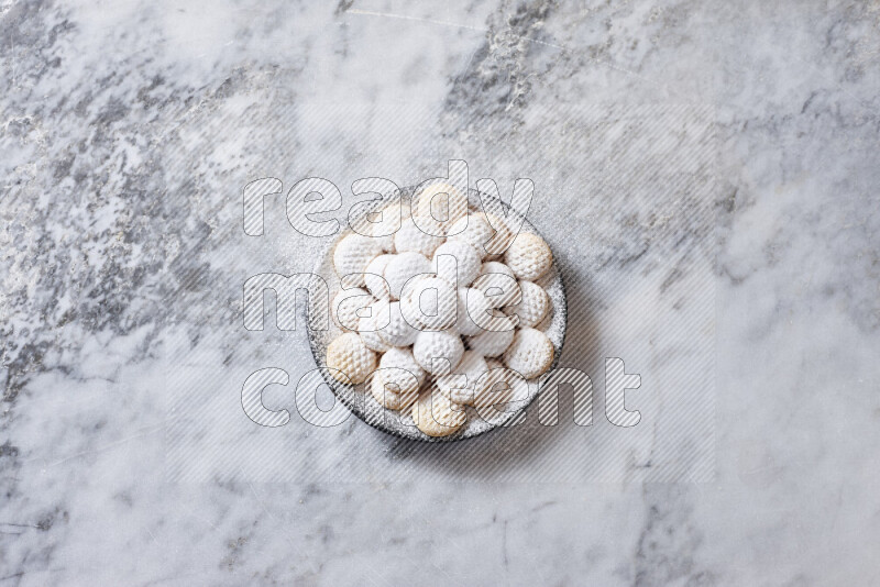 كحك في صحن فخار أسود على خلفية رخام رمادي