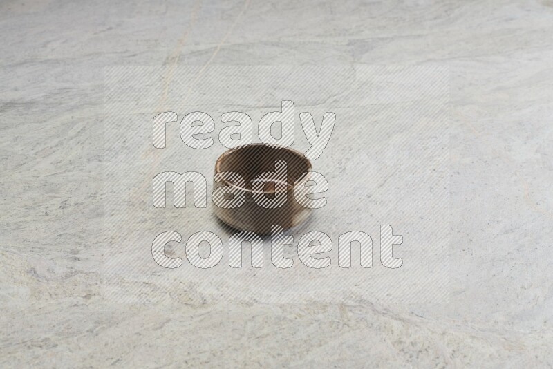 A brown pottery bowl on grey marble background