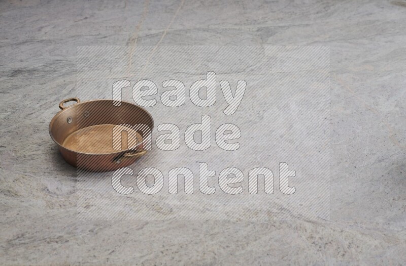 A small copper pan on grey marble background