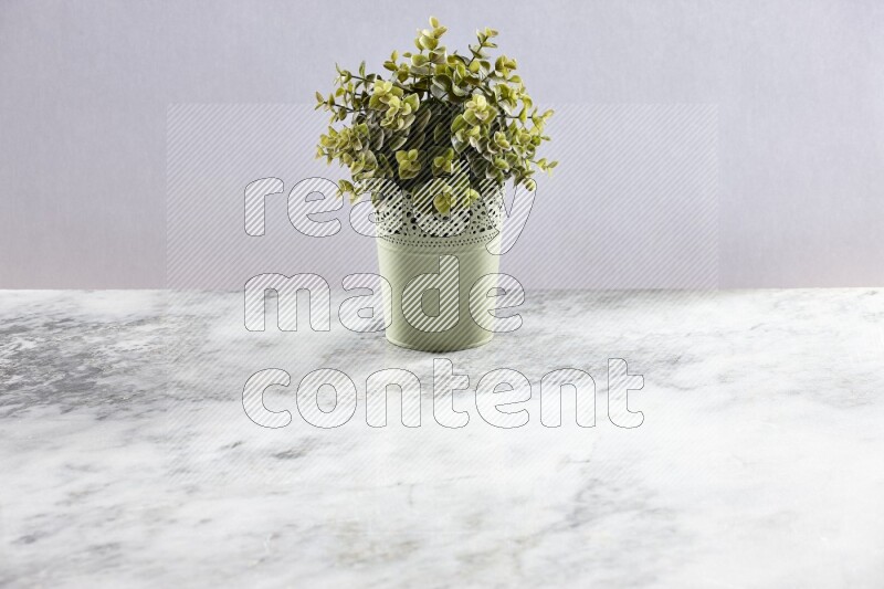 Artificial plant in green decorative pot on grey marble background