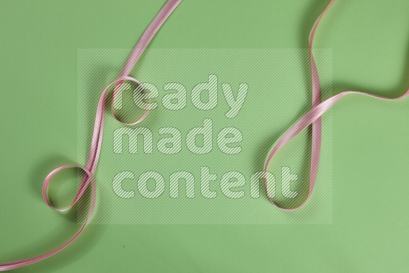 مجموعة من أدوات الخياطة والتفصيل زهرية اللون على خلفية خضراء