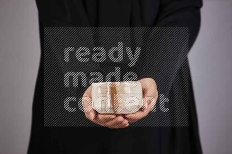 A woman in black abaya holding different pottery essentials in different positions