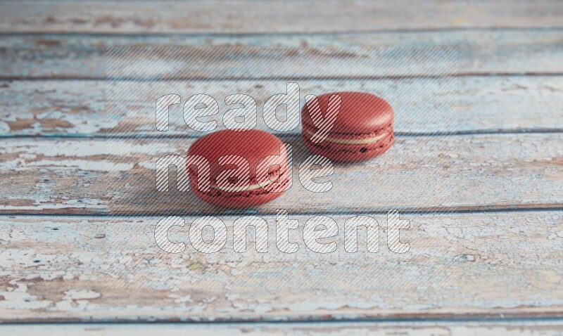 45º Shot of two Red Velvet macarons on light blue wooden background