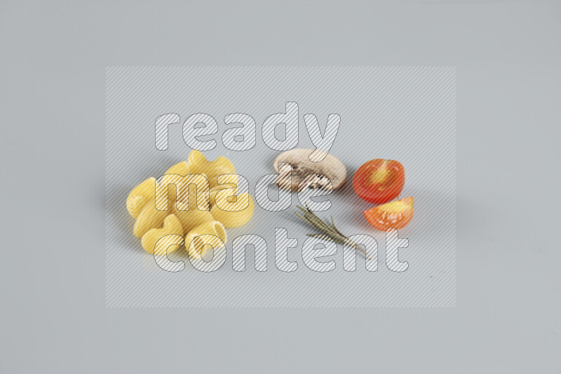 Raw pasta with different ingredients such as cherry tomatoes, garlic, onions, red chilis, black pepper, white pepper, bay laurel leaves, rosemary, cardamom and mushrooms on light blue background