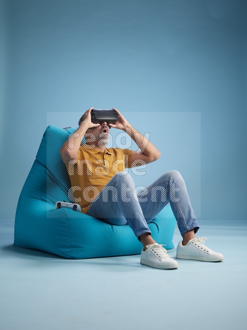 A man sitting on a blue beanbag and gaming with VR