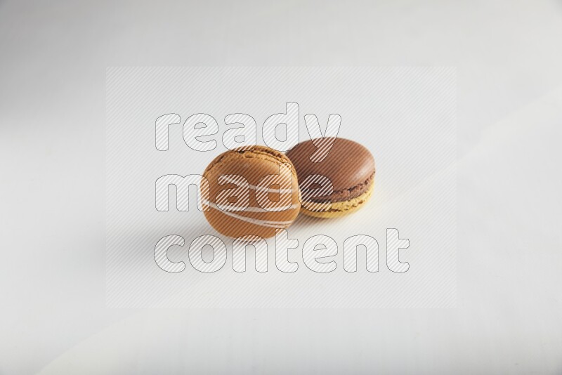 45º Shot of of two assorted Brown Irish Cream, and Yellow, and Brown Chai Latte macarons on white background