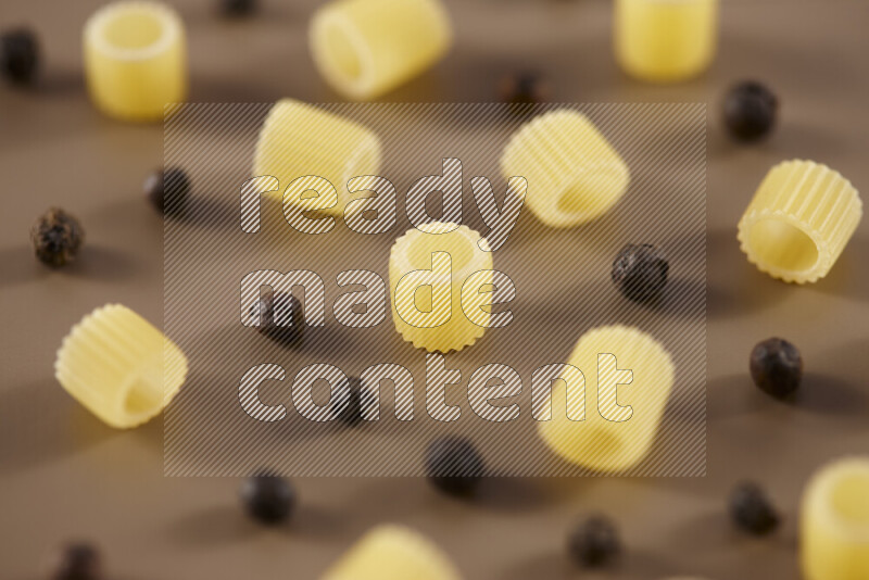 Raw pasta with different ingredients such as cherry tomatoes, garlic, onions, red chilis, black pepper, white pepper, bay laurel leaves, rosemary and cardamom on beige background
