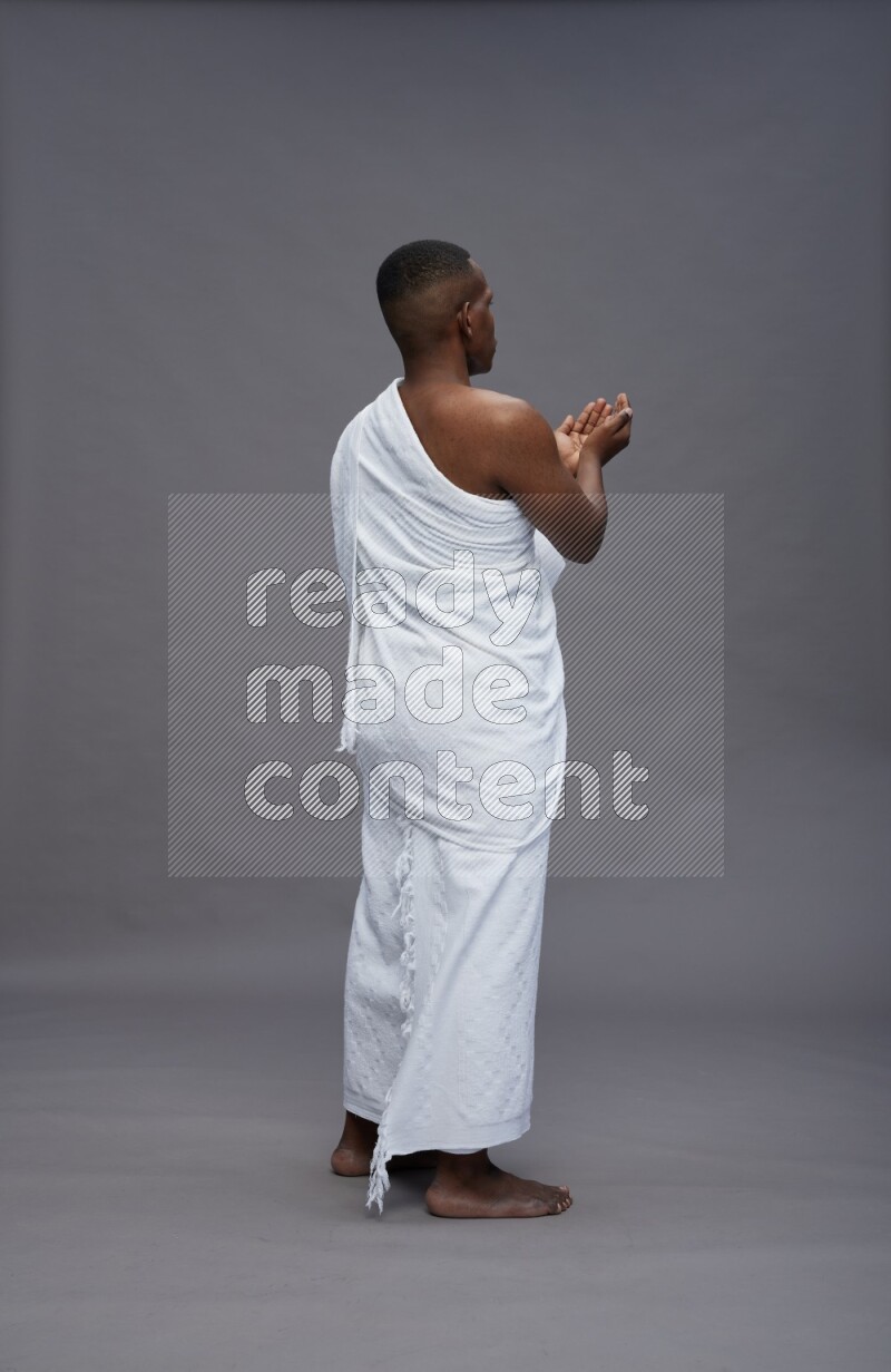 A man wearing Ehram Standing dua'a on gray background