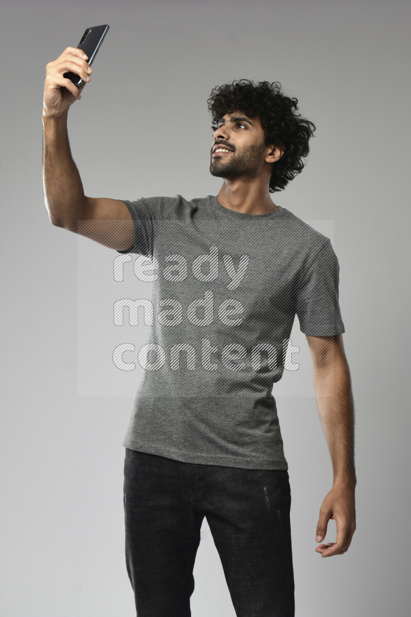 A man wearing casual standing and taking a selfie on white background