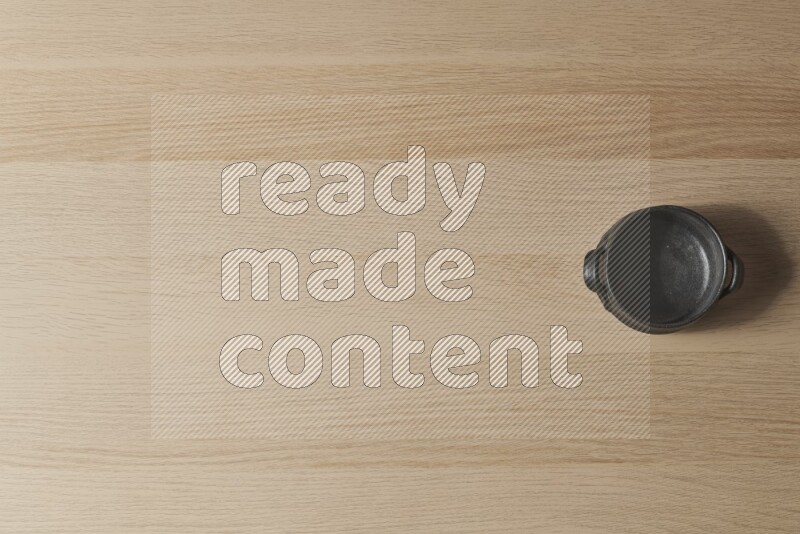 A black pottery bowl on light wooden background