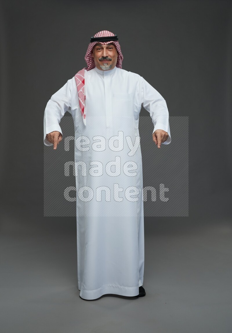Saudi man with shomag Standing Interacting with the camera on gray background