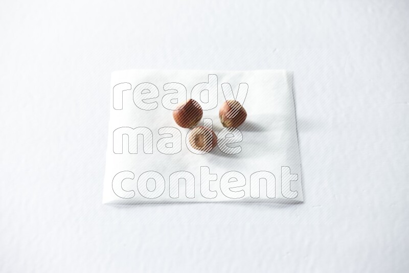3 hazelnuts on a piece of paper on a white background in different angles